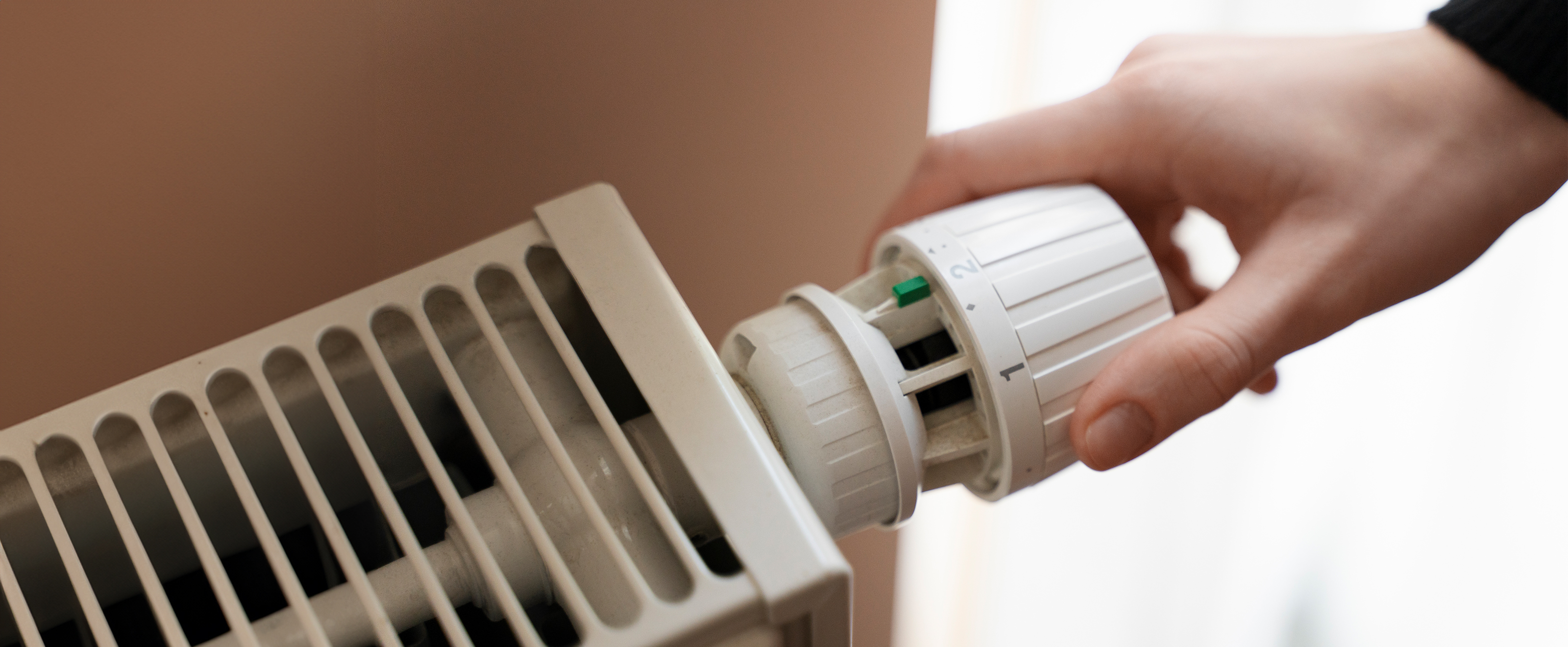close up photo of someone adjusting a thermostat on a radiator