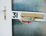 Photo of various envelopes sticking through a letterbox in a house door. The door is numbered with 31.