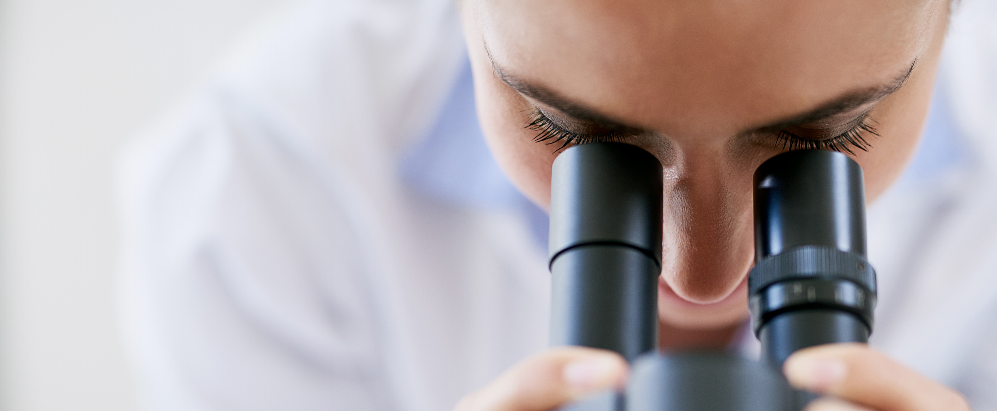 Close up photo of someone looking down a microscope