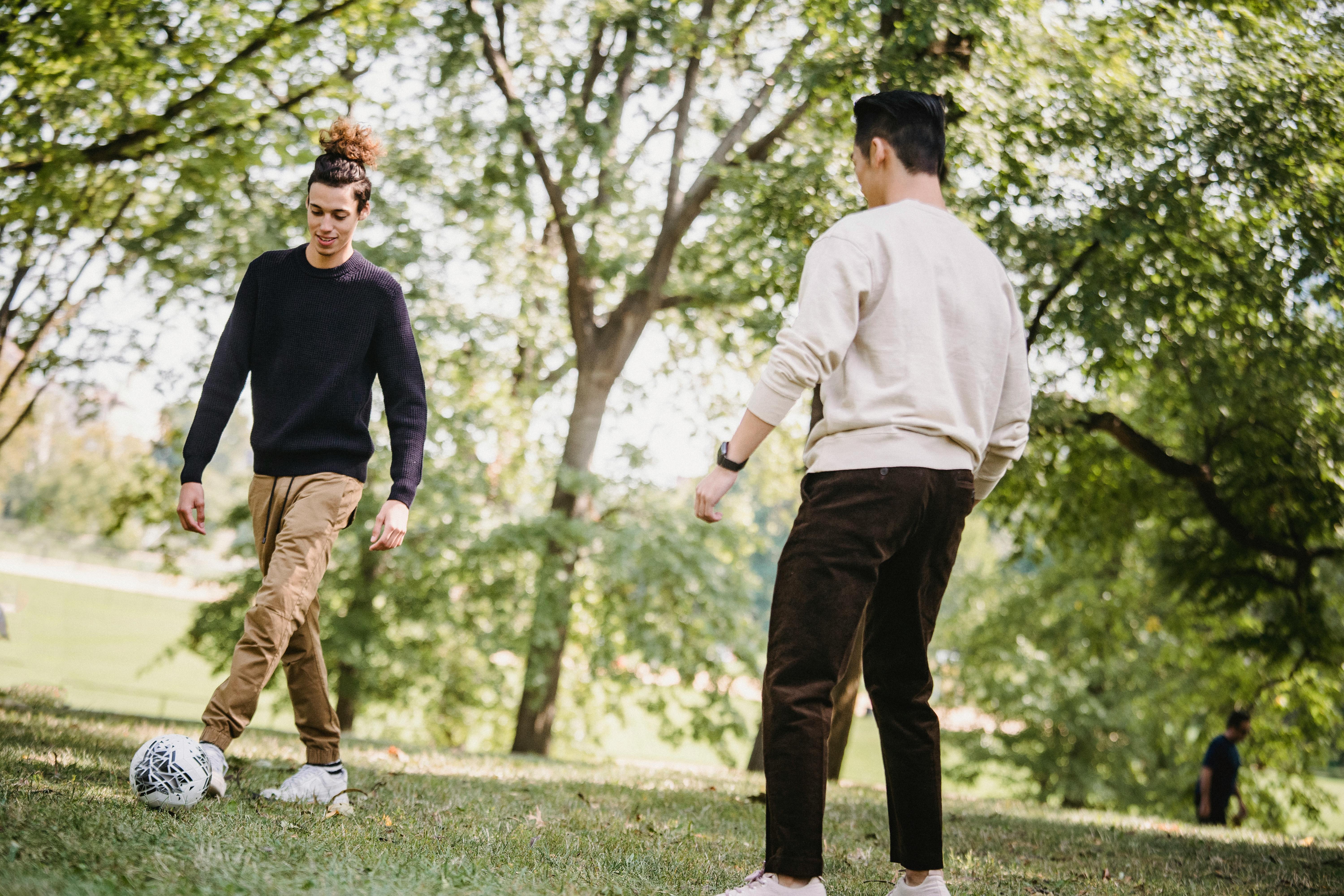 Photo of two young men kicking a football around in a grassy area