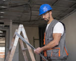 Photo of a workman standing in a property under construction. He is wearing a hard hat and other protective clothing