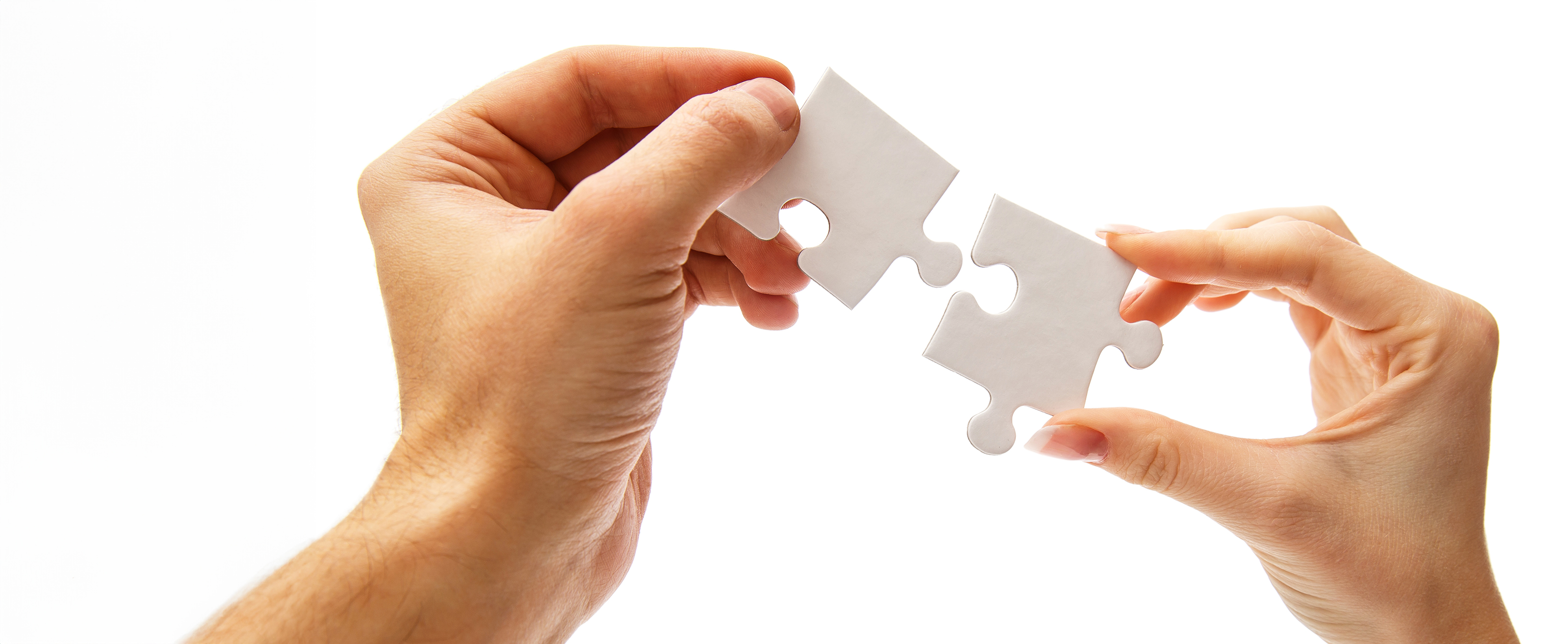 close up photo of someone holding a white jigsaw piece in each hand which they are trying to join together