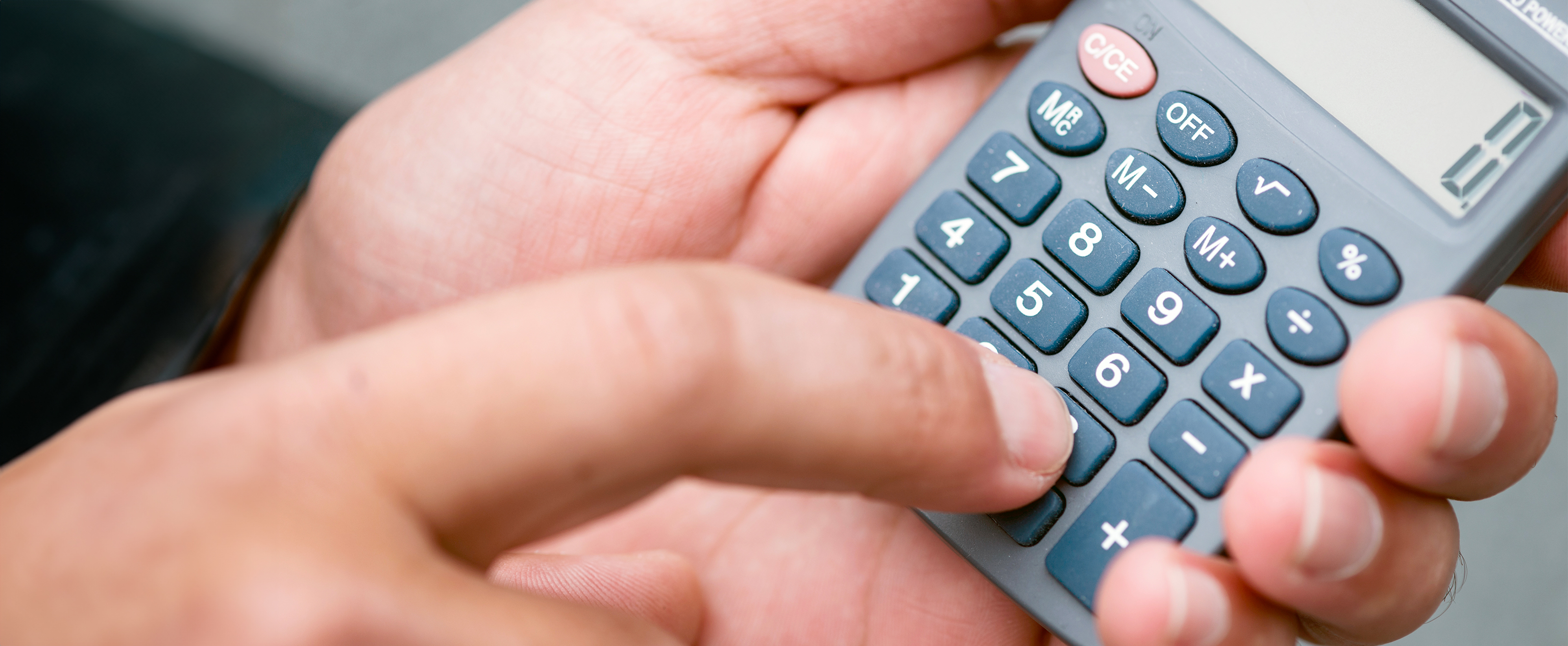 Close up photo of a man holding and using a pocket calculator