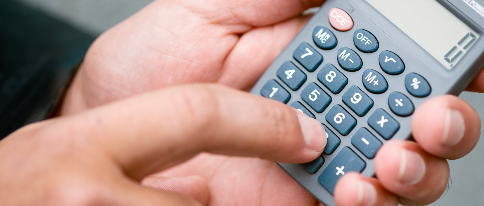 Close up photo of a man holding and using a pocket calculator