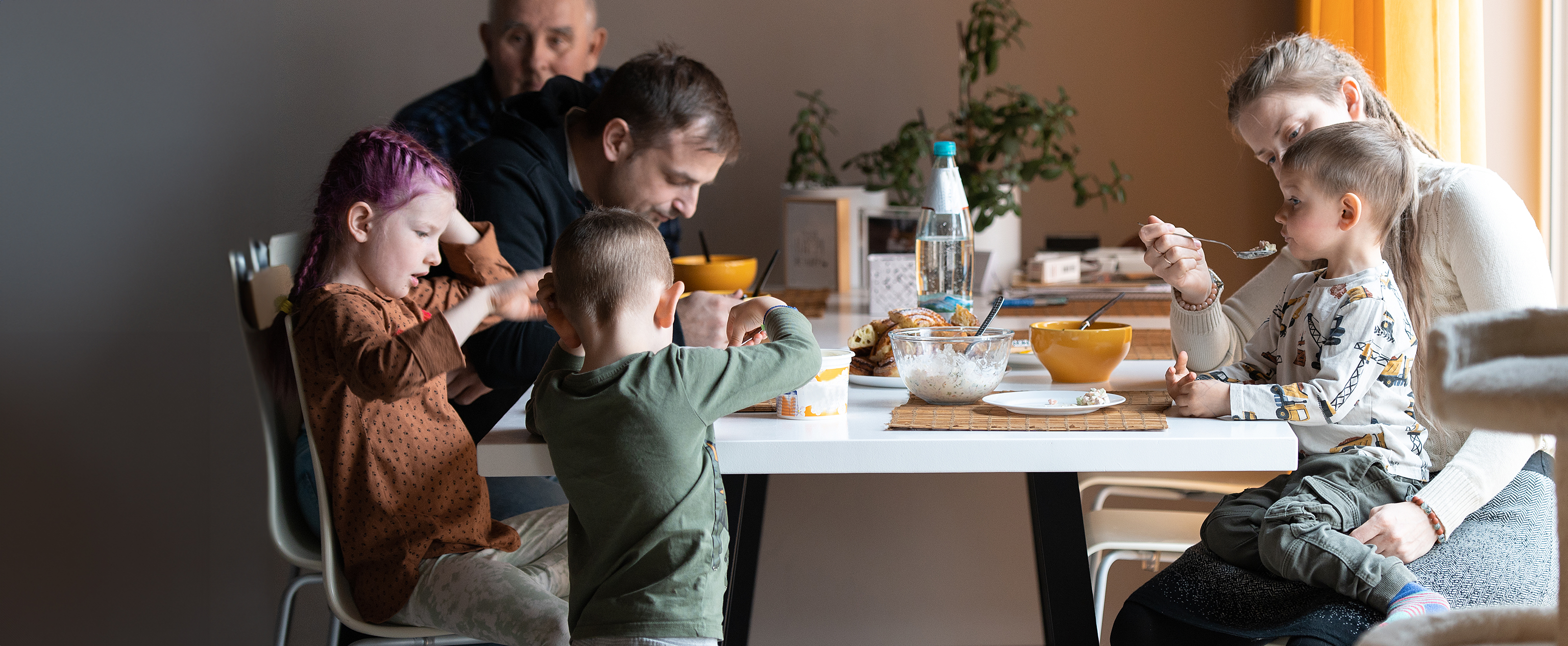 Photo of a multi-generational family sitting around a dining table sharing a meal