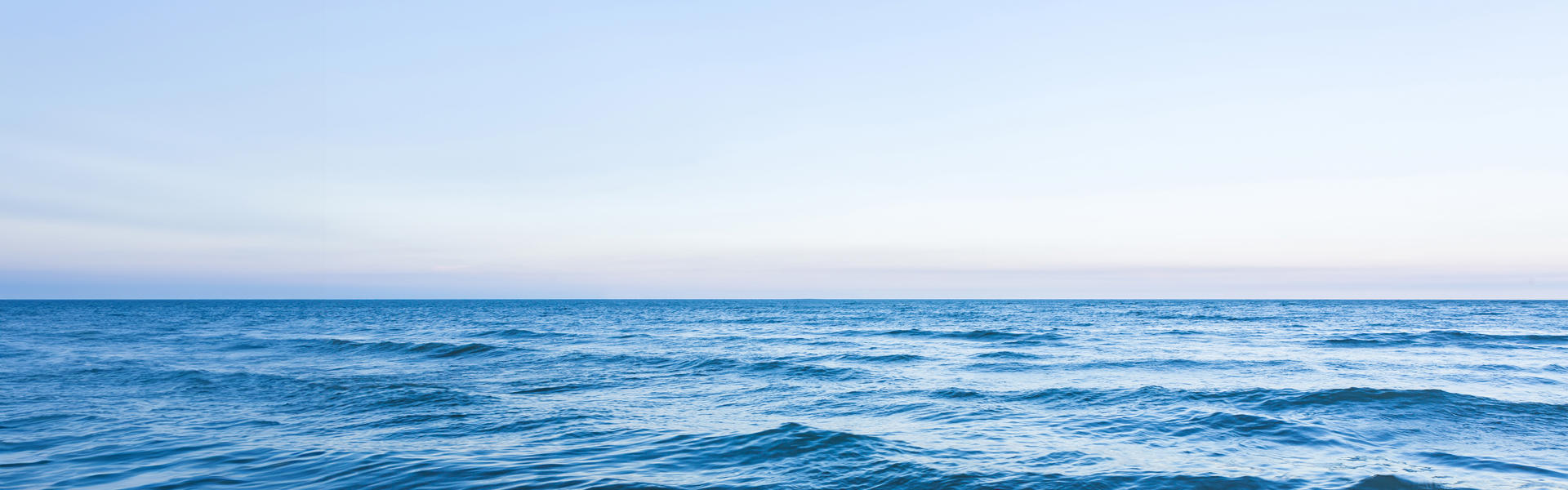 Panoramic photo showing a calm ocean with a blue sky
