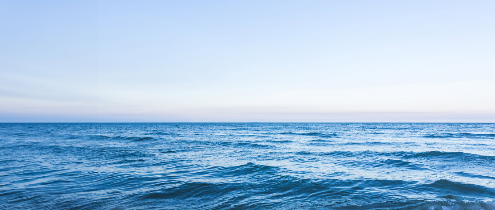 Panoramic photo showing a calm ocean with a blue sky