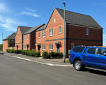 Photo of a small terrace of new build houses with a blue pickup truck in the foreground