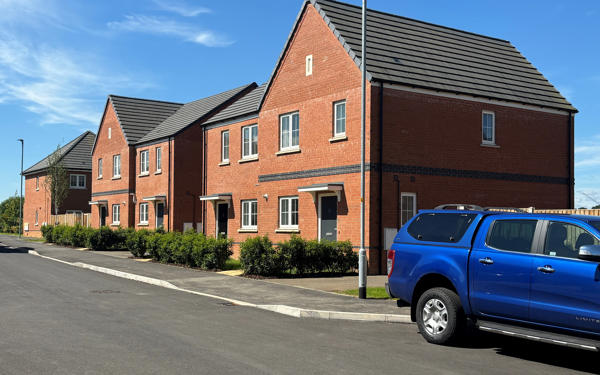 Photo of a small terrace of new build houses with a blue pickup truck in the foreground