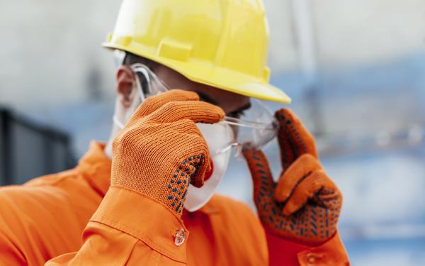 Workman In Hard Hat Adjusting Goggles