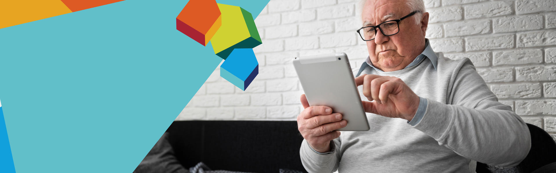 Photo of an older man using a tablet computer while sitting on a sofa