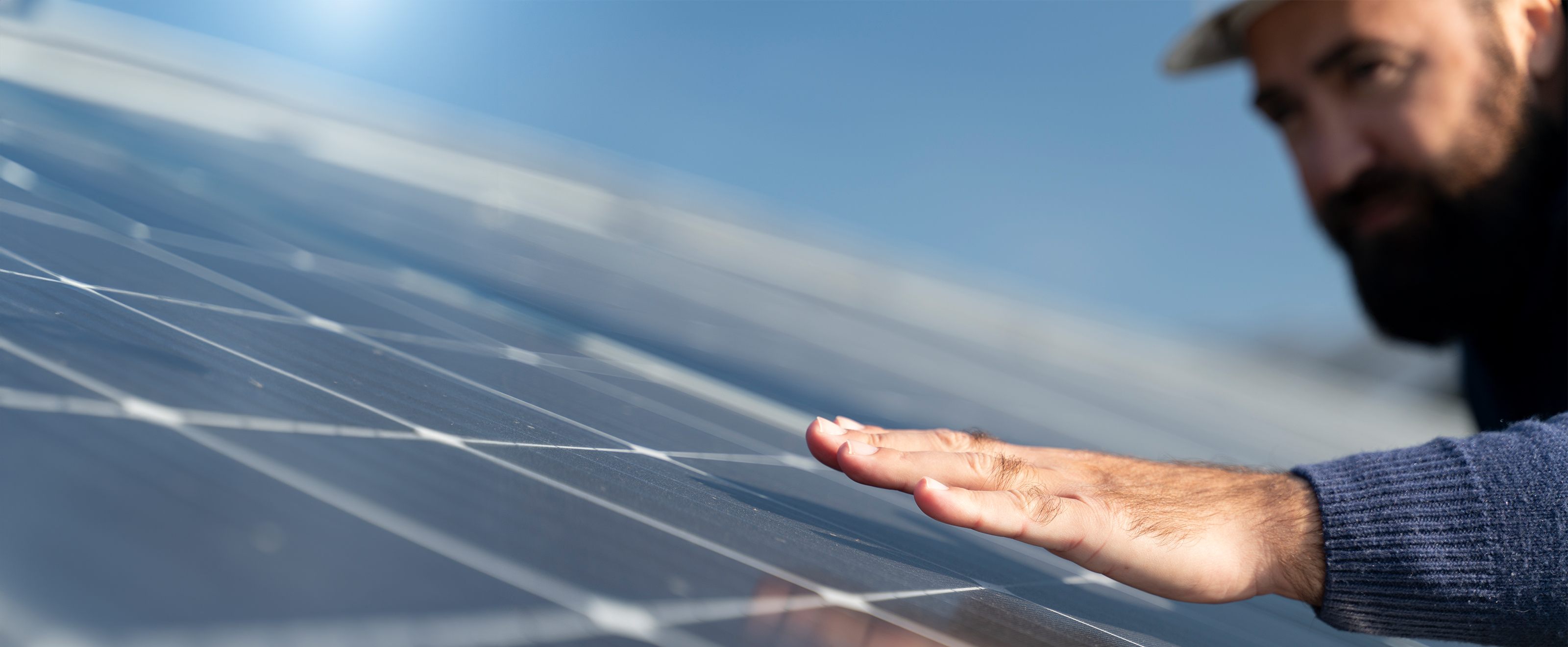 Close up photo of a man inspecting solar panels on a roof