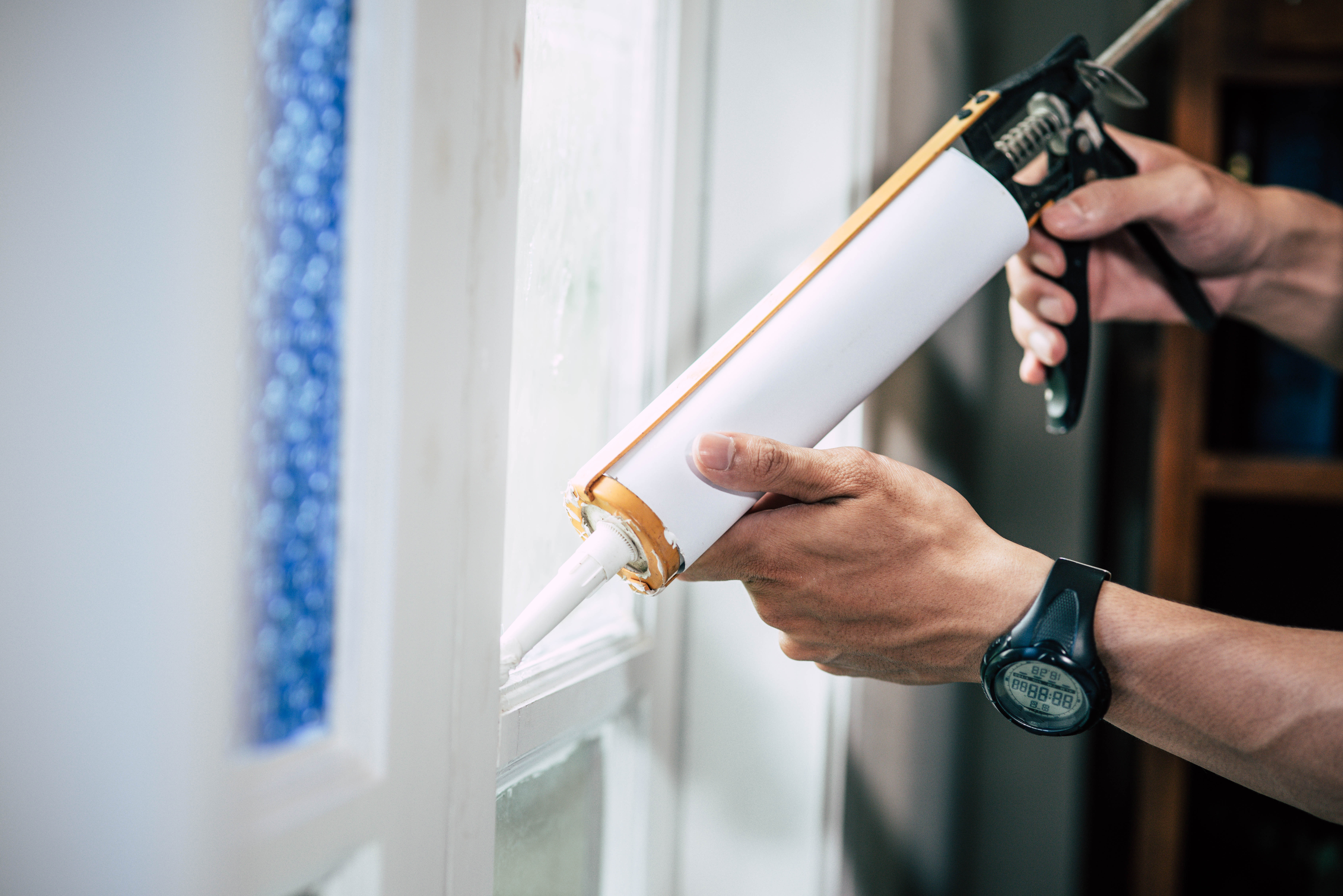 Close up photo of someone applying sealant around a window