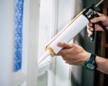 Close up photo of someone applying sealant around a window