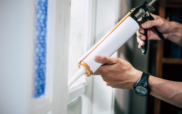 Close up photo of someone applying sealant around a window