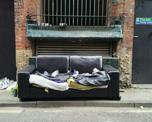 Photo of a ruined black leather sofa dumped in a city street